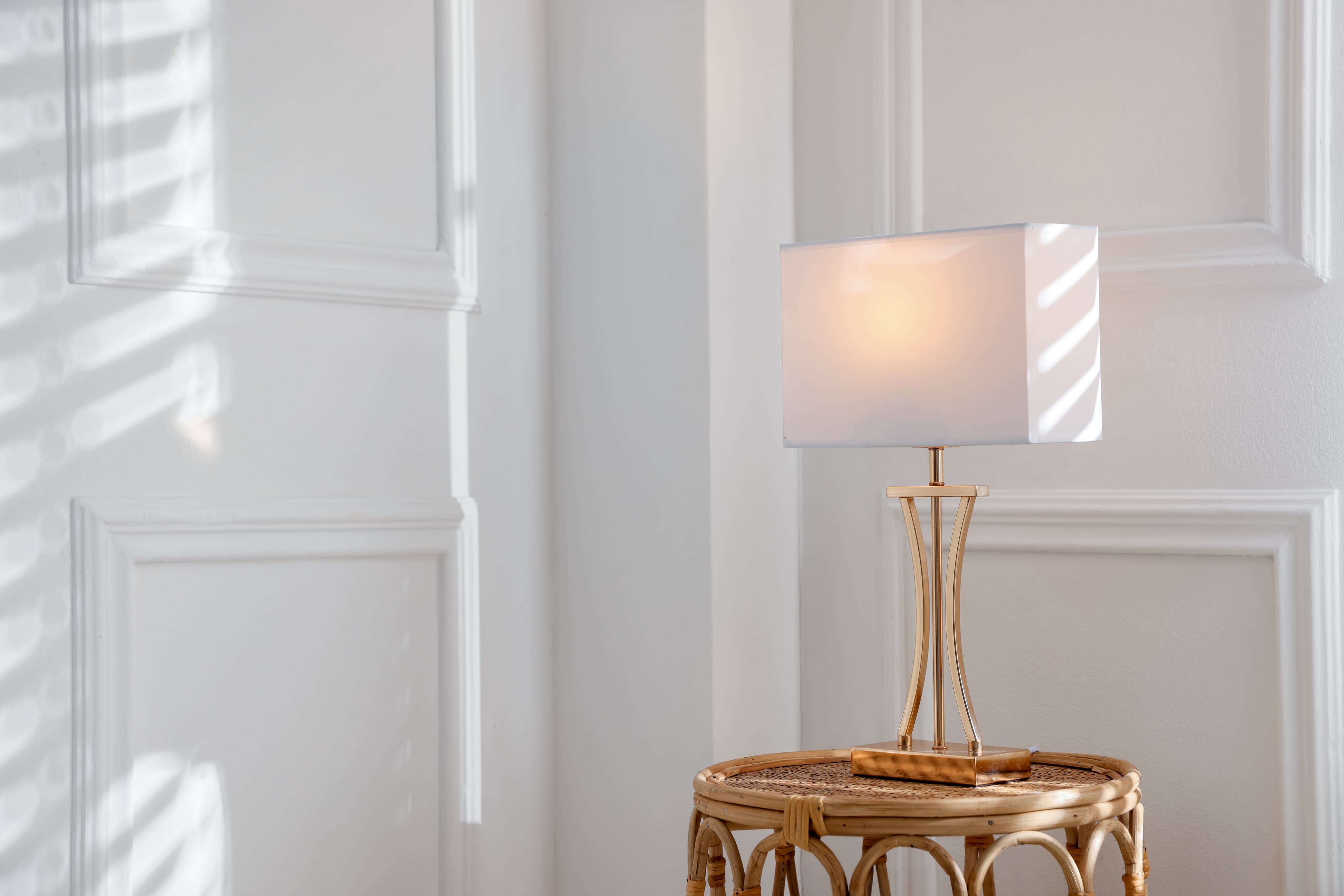 stylish-lamp-rattan-table-near-white-wall-indoors-space-text.jpg